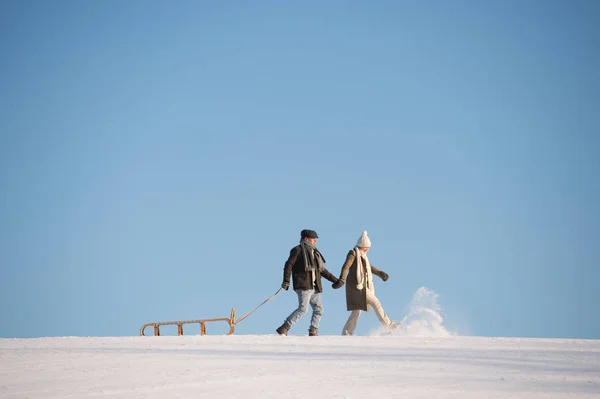 Vacker äldre par på en promenad att dra släden, vinterdag. — Stockfoto
