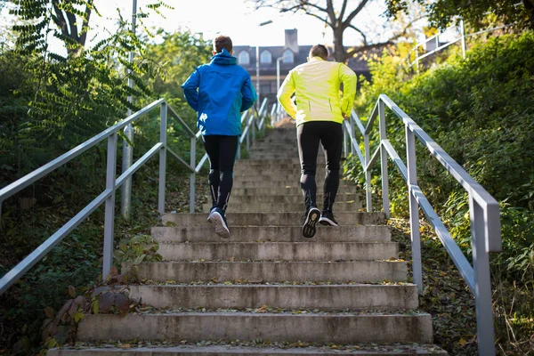Два спортсмена бегут по лестнице в солнечную осень, вид сзади . — стоковое фото
