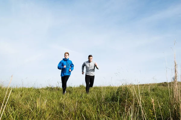 Two young hipster athletes running in sunny autumn nature — Stock Photo, Image