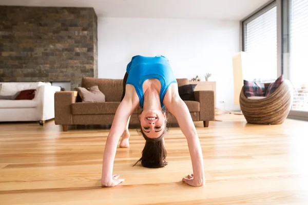 Young woman exercising at home, stretching, doing bridge pose.