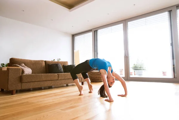 Junge Frau übt zu Hause, dehnt sich, macht Bridge-Pose. — Stockfoto