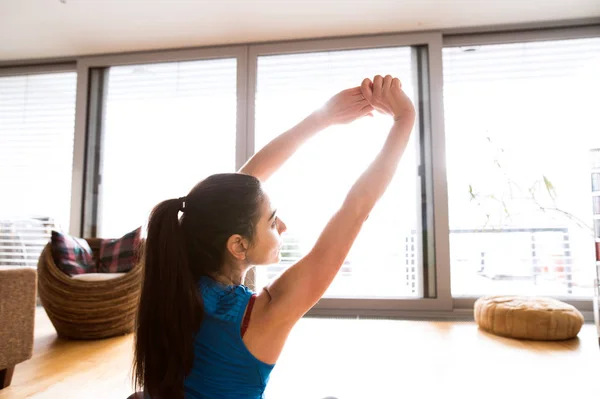 Ung kvinna träna hemma, sträcker armarna. — Stockfoto