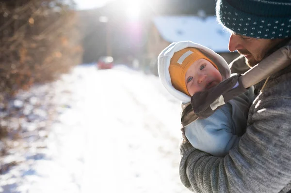 Padre sosteniendo a su hijo en portabebés. Naturaleza soleada de invierno . —  Fotos de Stock