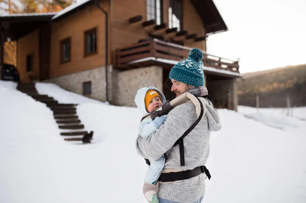 Father holding his son in baby carrier. Sunny winter nature. — Stock Photo, Image