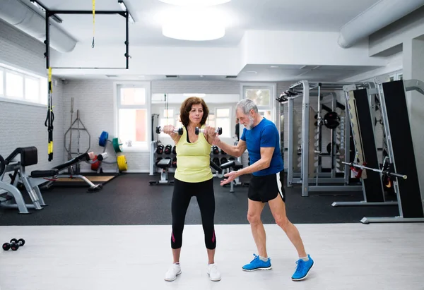Couple sénior en salle de gym travaillant avec des poids — Photo
