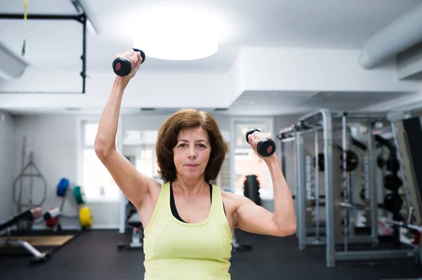 Senior vrouw in sportschool trainen met gewichten. — Stockfoto