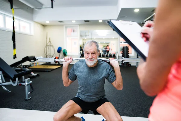 Hombre mayor en el gimnasio haciendo ejercicio con pesas — Foto de Stock