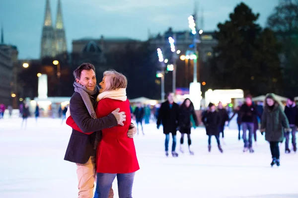 Beautiful senior couple ice skating in city centre. Winter