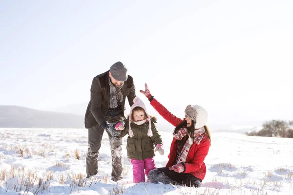 Pai e mãe com sua filha, brincando na neve . — Fotografia de Stock