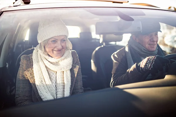 Senior couple in winter clothes driving a car — Stock Photo, Image