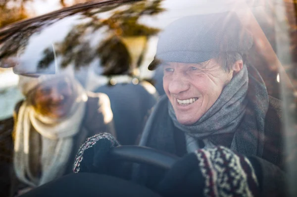 Coppia anziana in abiti invernali alla guida di una macchina — Foto Stock