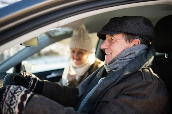 Seniorenpaar in Winterkleidung am Steuer eines Autos — Stockfoto