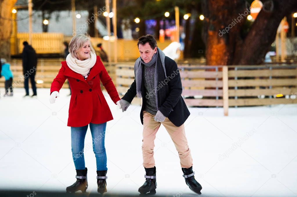 Beautiful senior couple ice skating in city centre. Winter