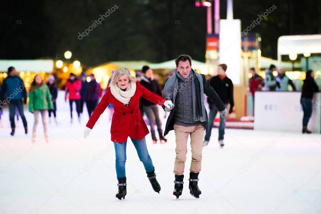 Beautiful senior couple ice skating in city centre. Winter