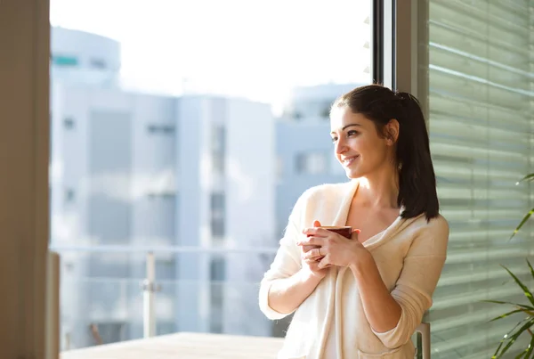 Woman relaxing on balcony holding cup of coffee or tea — Stock Photo, Image