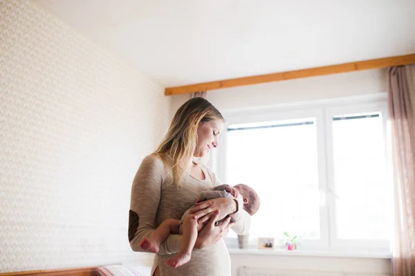 Bela jovem mãe segurando bebê filho em seus braços — Fotografia de Stock