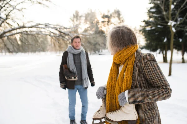 Pareja mayor en invierno con patines de hielo yendo a la pista de patinaje . — Foto de Stock