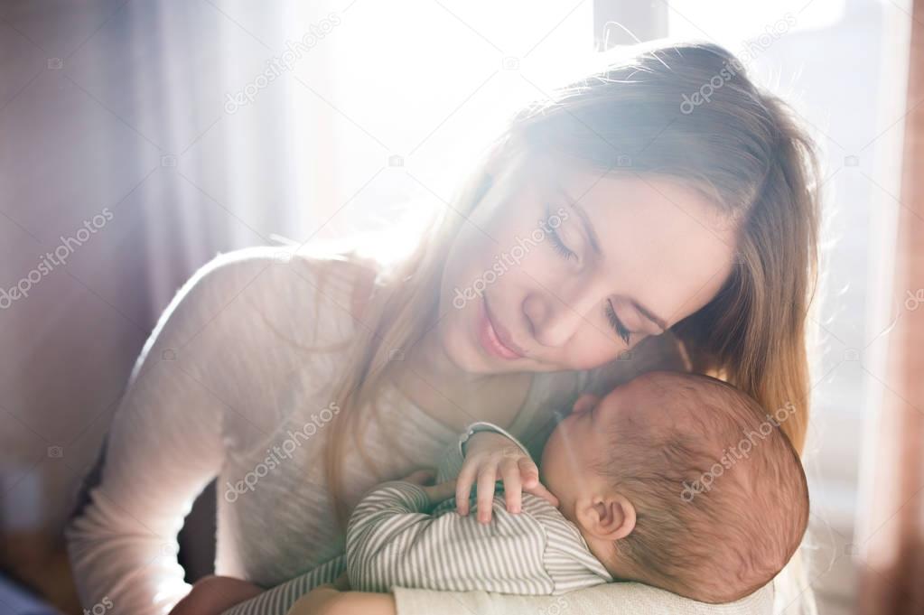 Beautiful young mother holding baby son in her arms