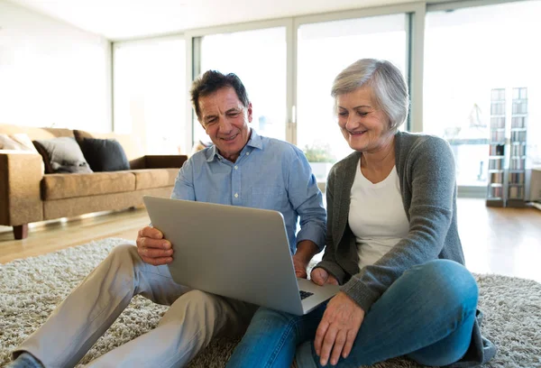 Couple âgé assis sur le sol, travaillant sur un ordinateur portable — Photo