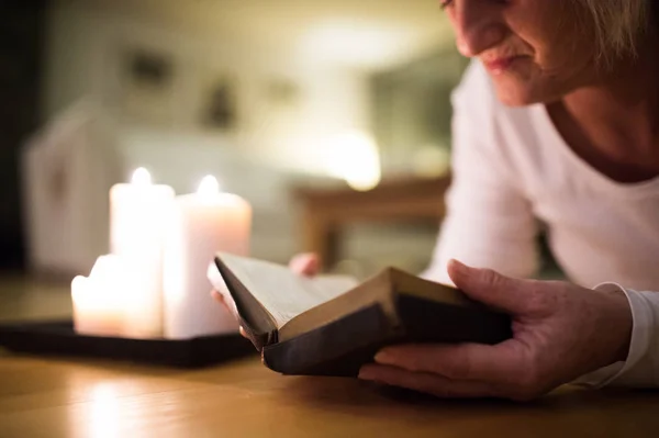 Нерозпізнаний жінка читання Біблії. Палаючі свічки поруч з нею. — стокове фото