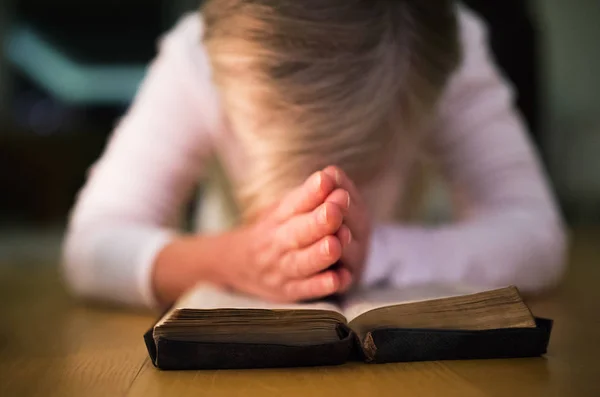 Неузнаваемая женщина молится, сжимая руки на библии — стоковое фото