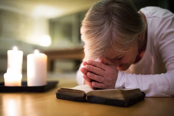 Senior vrouw bidden, handen geklemd samen op haar Bijbel. — Stockfoto