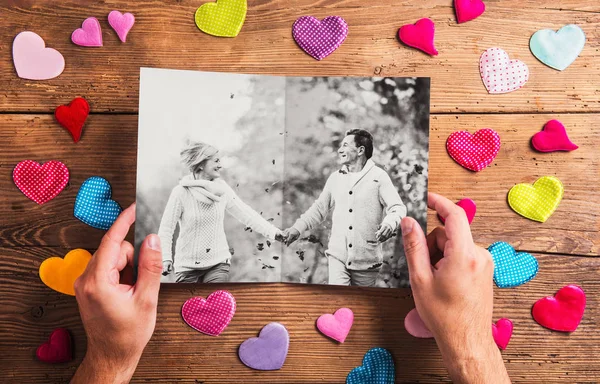 Руки держат фотографию пожилой пары, красочные сердца. Студия — стоковое фото