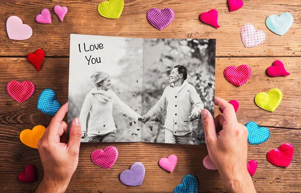 Hands holding picture of senior couple, colorful hearts. Studio — Stock Photo, Image