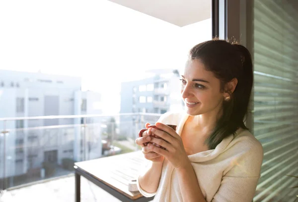 Žena uvolňující na balkon hospodářství šálek kávy nebo čaje — Stock fotografie