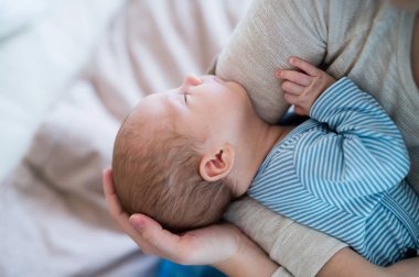 Yatağın üstüne oturan tanınmaz halde anne holding yeni doğan bebek oğul