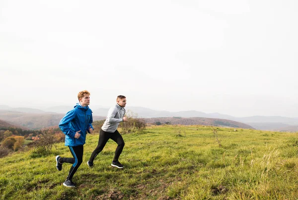 Two young hipster athletes running in sunny autumn nature — Stock Photo, Image