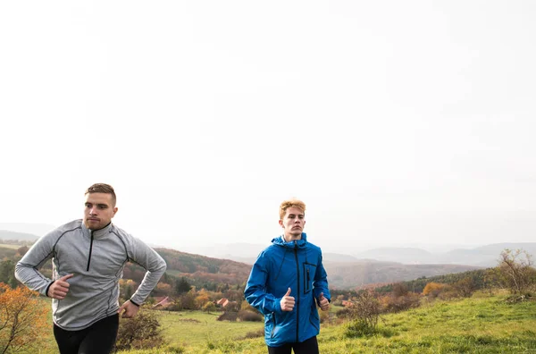 Two young hipster athletes running in sunny autumn nature — Stock Photo, Image