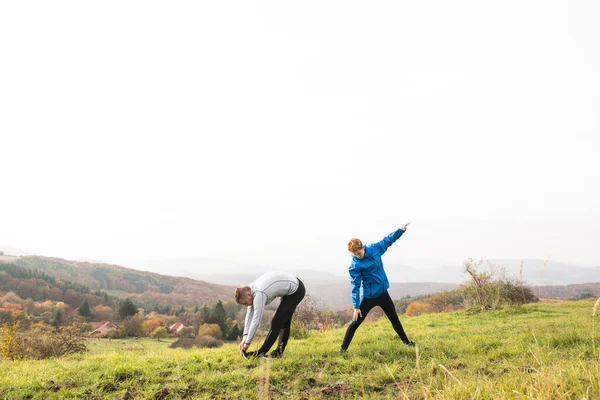 Två unga hipster löpare i soliga höst naturen stretching benen — Stockfoto