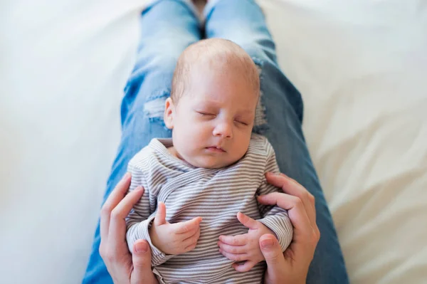 Oigenkännlig mor med sovande baby son sitter på sängen — Stockfoto