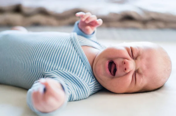 Söta nyfödda baby pojke ligga på sängen, grät. Närbild. — Stockfoto