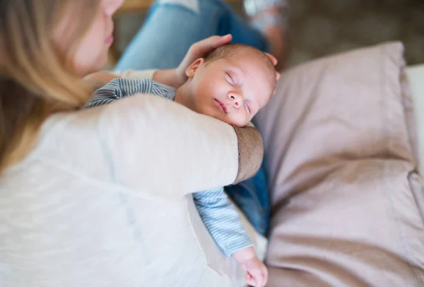 Felismerhetetlen anya gazdaság alvó baba fiú ül ágyas — Stock Fotó