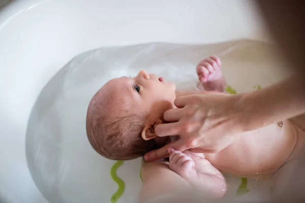 Irreconocible madre bañando a su hijo en blanco pequeño murciélago de plástico — Foto de Stock