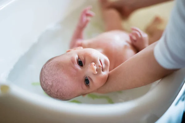 Irreconocible madre bañando a su hijo en blanco pequeño murciélago de plástico — Foto de Stock