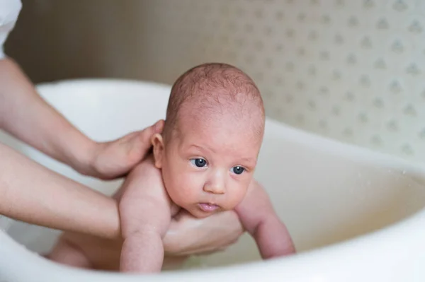 Oigenkännlig mor badar sin son i vit liten plast bat — Stockfoto