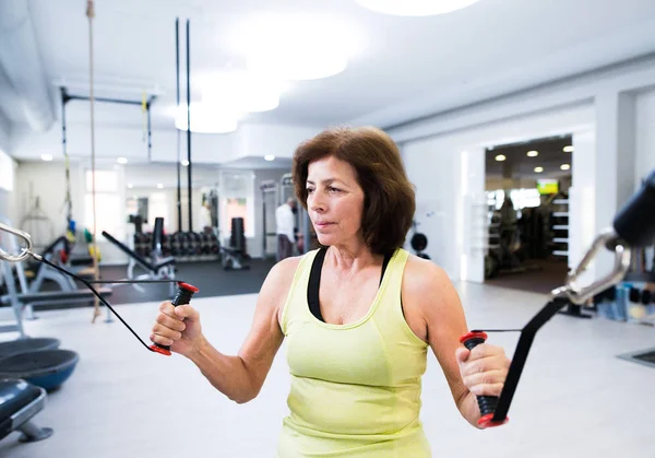 Femme âgée dans la salle de gym travailler avec des poids . — Photo
