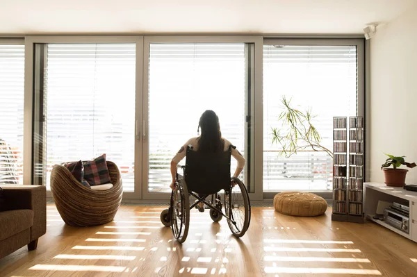 Молодая женщина-инвалид в инвалидной коляске дома, вид сзади . — стоковое фото