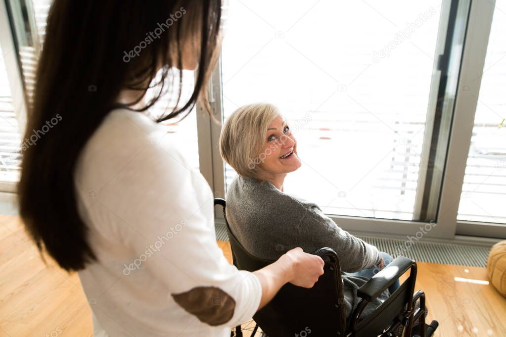 Disabled senior woman in wheelchair with her young daugher.