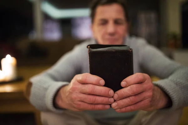 Älterer Mann betet, Bibel in der Hand, brennende Kerzen hinter sich — Stockfoto