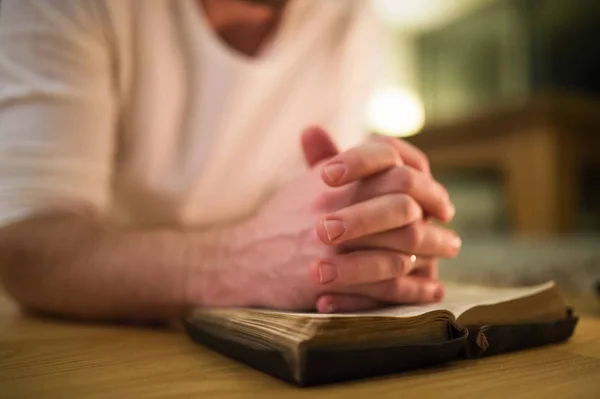 Hombre irreconocible rezando, arrodillado en el suelo, manos sobre Bibl — Foto de Stock