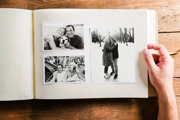 Mão segurando álbum de fotos com fotos de casal sênior. Estúdio — Fotografia de Stock