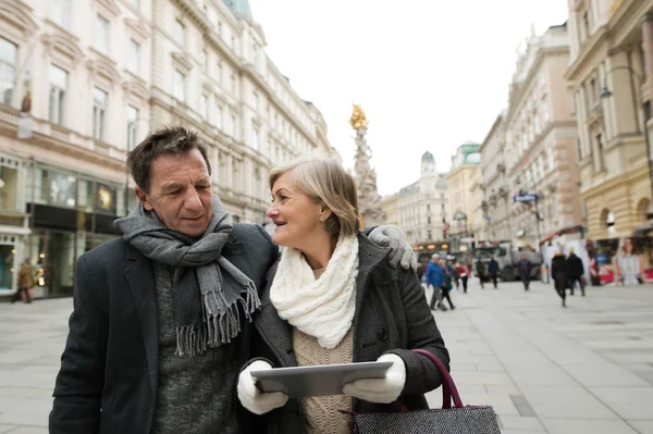 Schönes Senioren-Paar mit Tablet auf Spaziergang in der Innenstadt. — Stockfoto