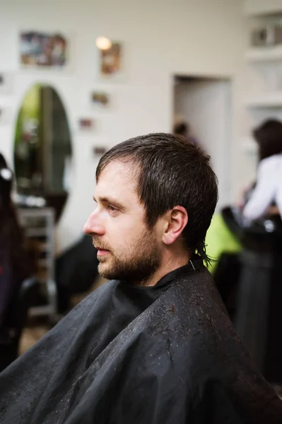 Молодой человек в парикмахерской, делает новую стрижку . — стоковое фото