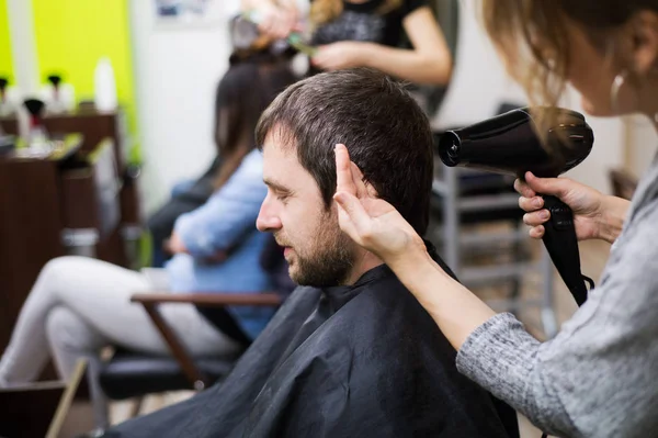 Coiffeur professionnel séchant les cheveux de son beau client . — Photo