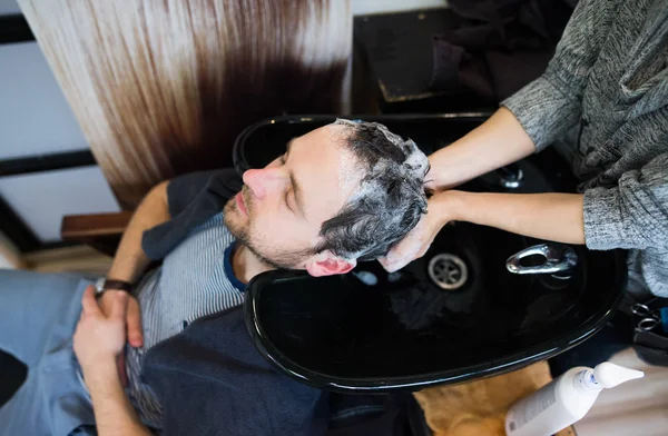 Професійний перукар миє волосся до її красивого клієнта . — стокове фото