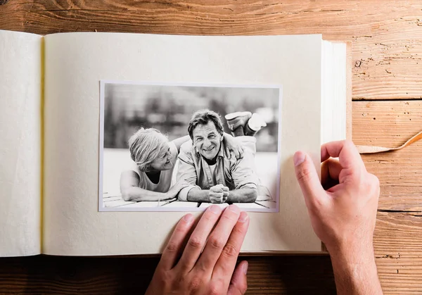 Рука держит фотоальбом с фотографиями пожилой пары. Студия — стоковое фото